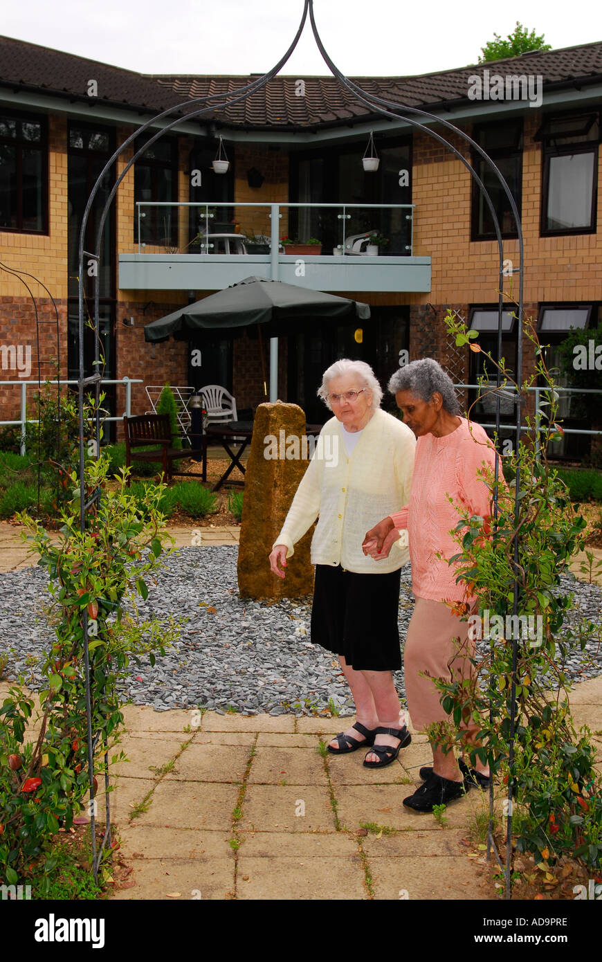 Two elderly residents of care home for dementia sufferers walking in