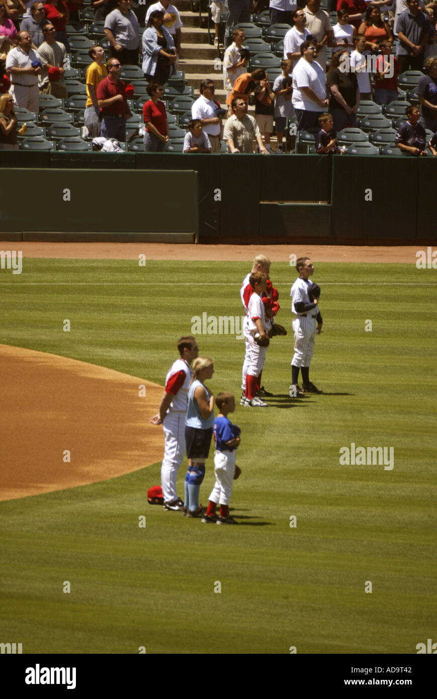 Baseball players and family members pause for a playing on the national ...