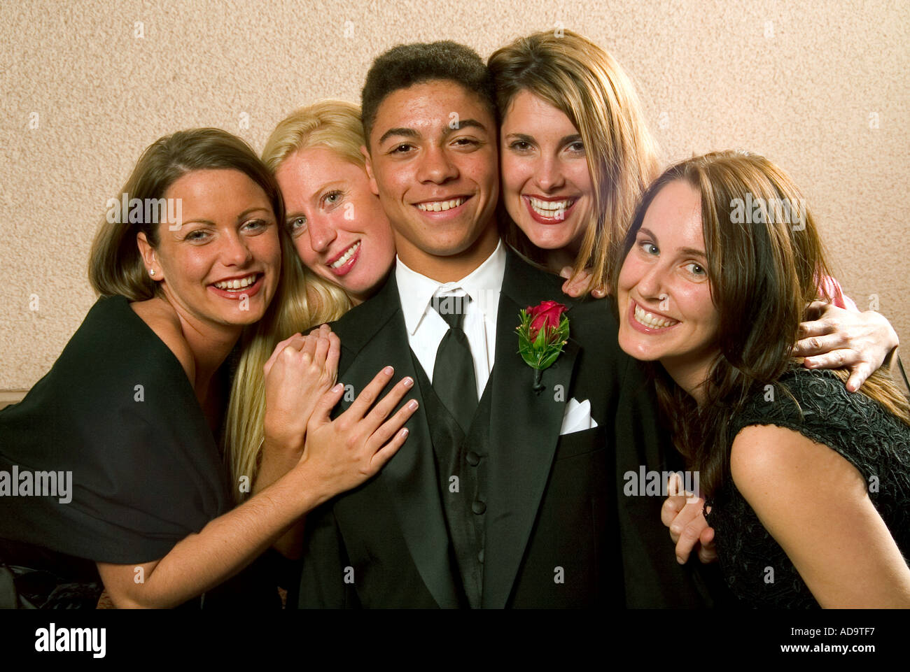 A happy young groomsman is surrounded by lovely ladies at the reception for a formal Catholic wedding in Costa Mesa CA Stock Photo