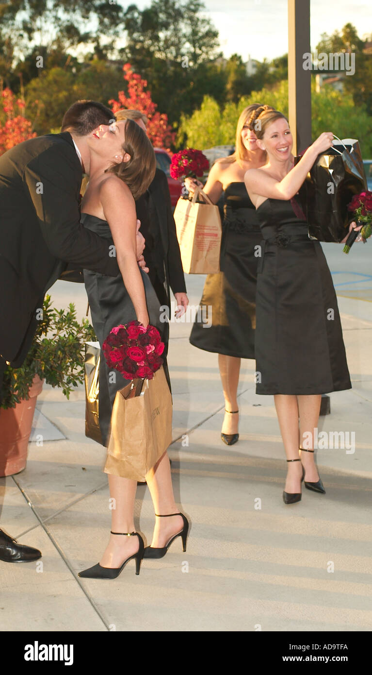 An arriving bridesmaid gets a kiss from a groomsman as she and the other bridesmaids arrive for a formal Catholic wedding in Lag Stock Photo