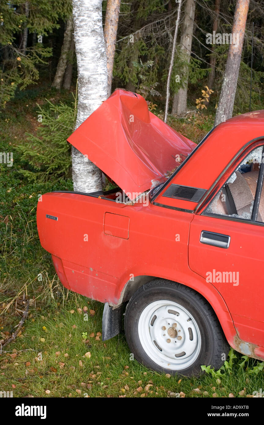 The busted rear end and trunk of a red Lada hitting a tree , Finland Stock Photo