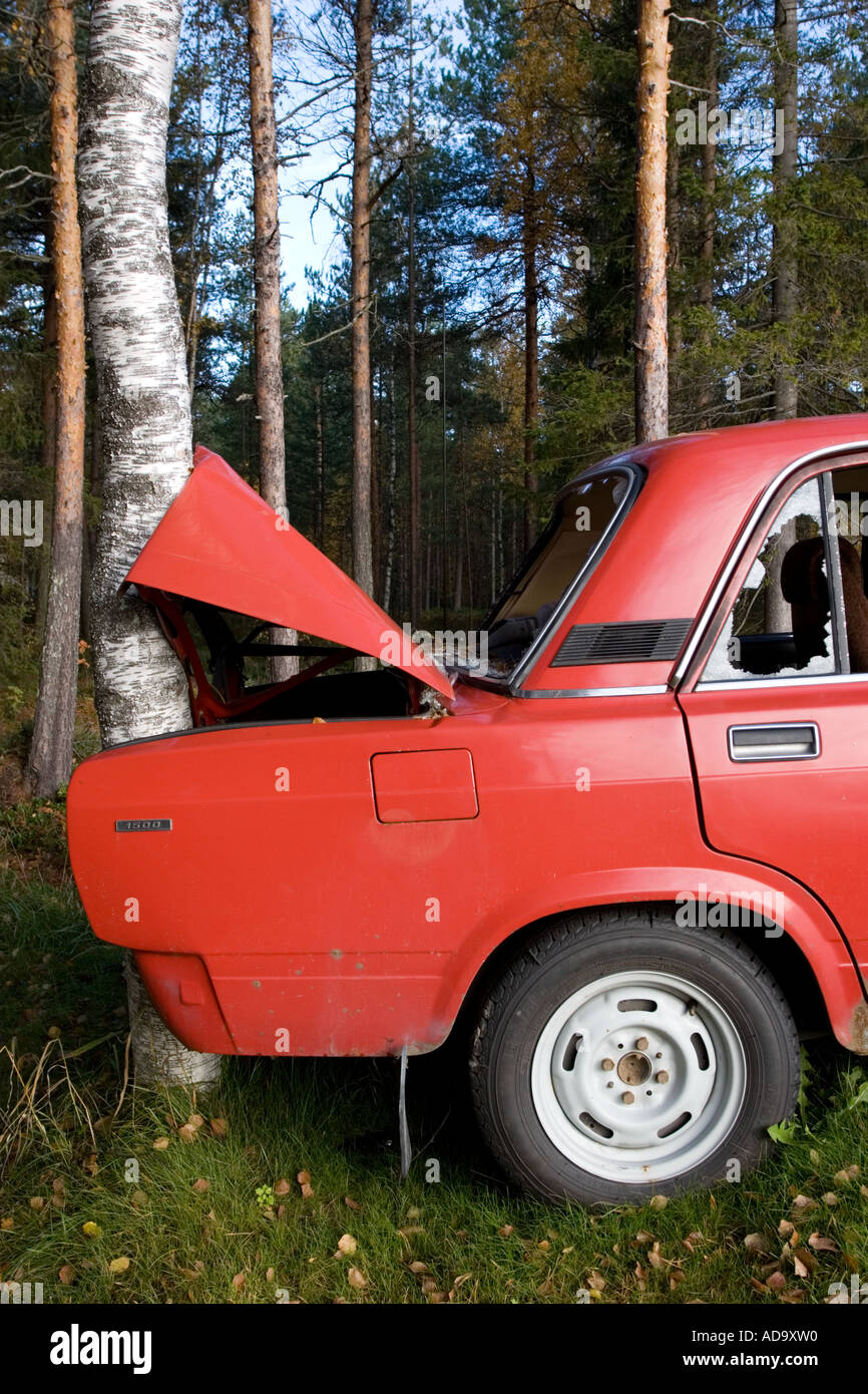 The busted rear end and trunk of a red Lada hitting a tree , Finland Stock Photo