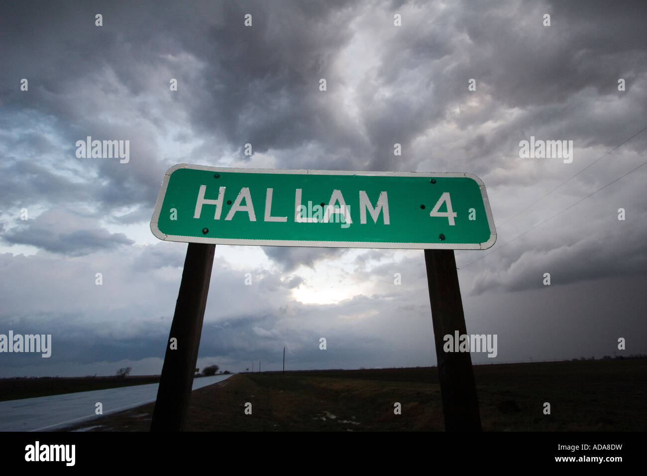 Sign marking Hallam, Nebraska, with storm clouds in background Stock