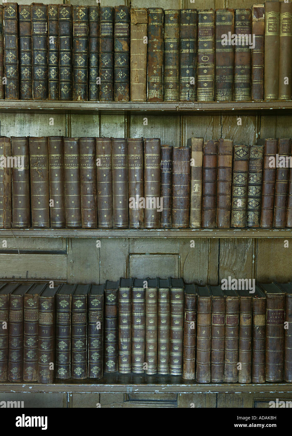 Very old historical traditional bookcase covered in old large books placed in a large Norfolk properties library Stock Photo