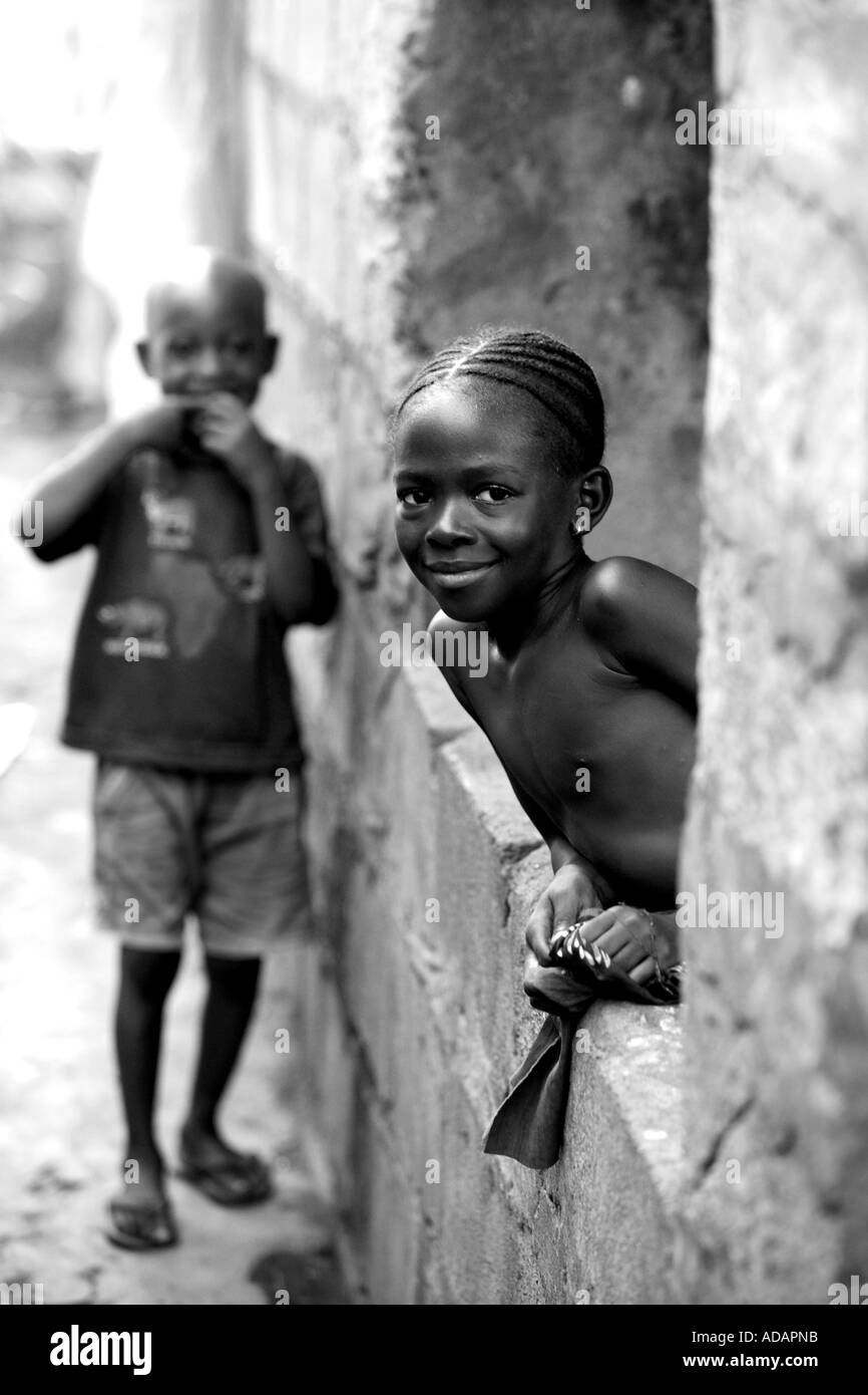 Vertical black and white portrait of two children in street in sierra leone smiling at camera freetown west africa
