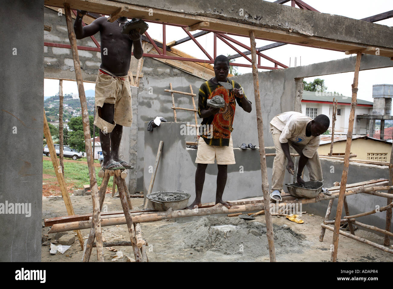 Horizontal environmental portrait of builders working on site in street in Freetown, Sierra