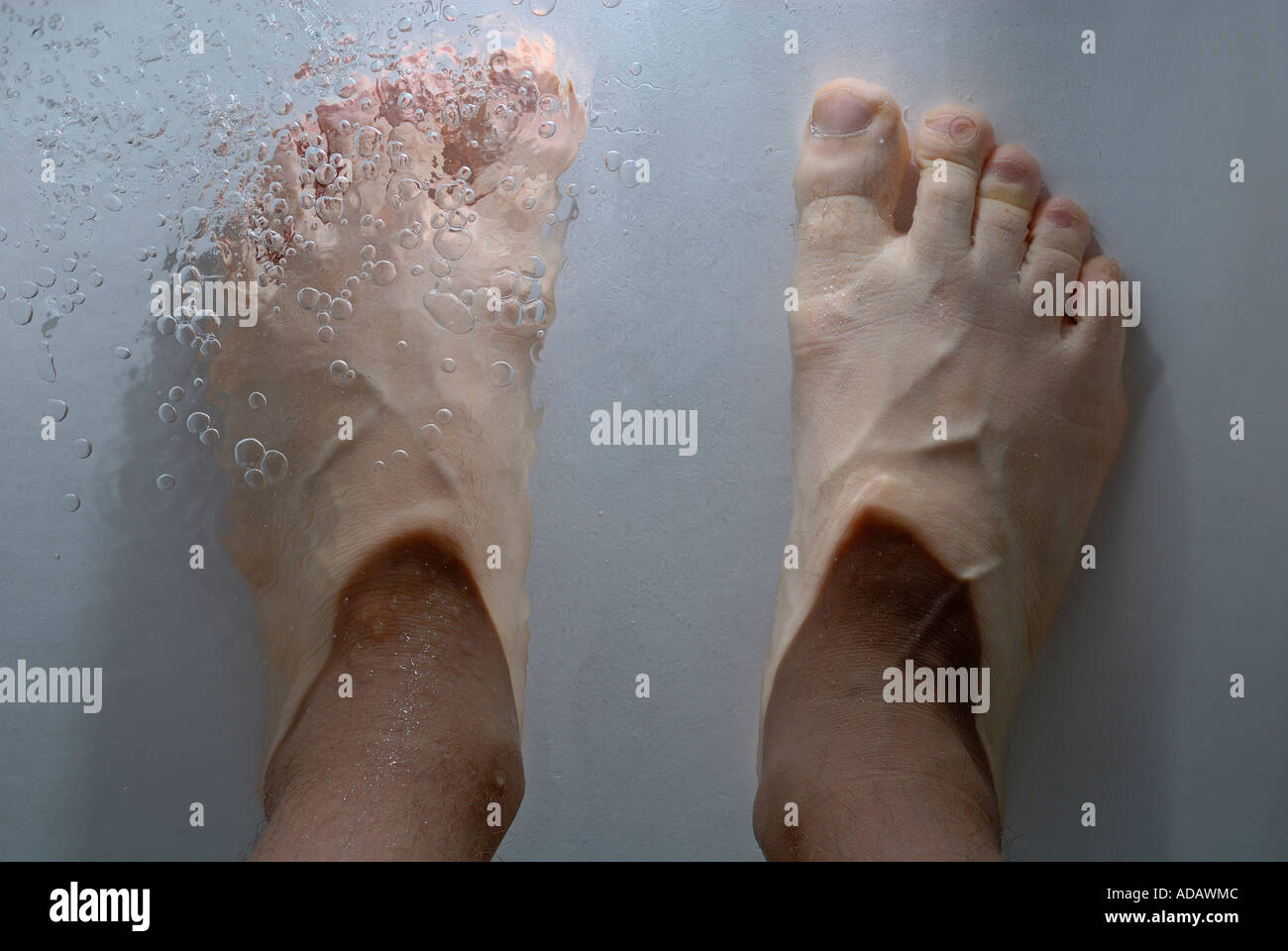 Man's feet submerged in a bathtub - point of view. Stock Photo