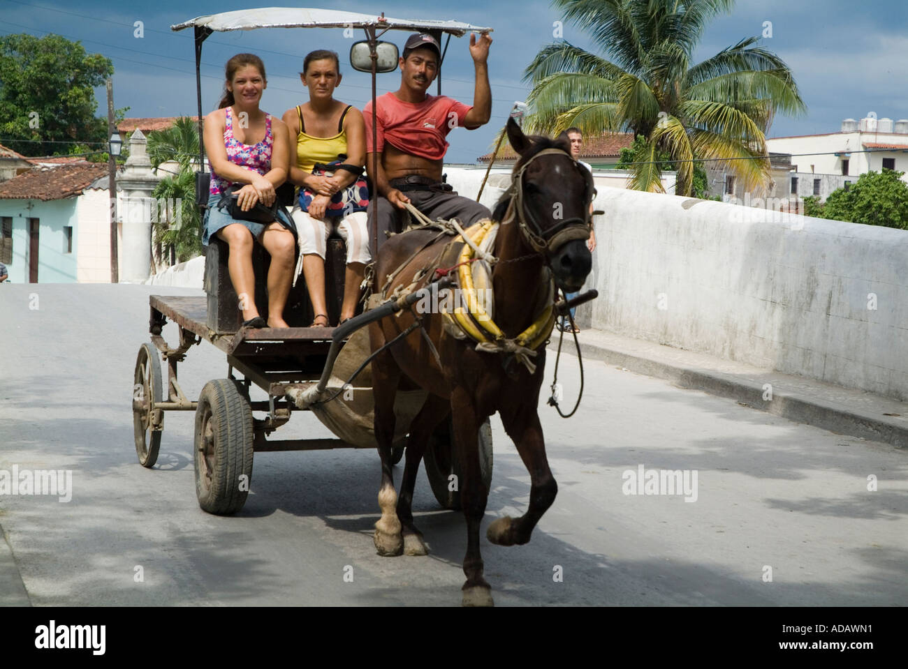Taxi driver riding a horse cart with tourists across the Rio Yayabo bridge, Sancti Spiritus, Cuba. Stock Photo
