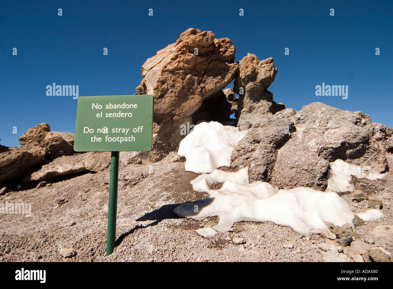 Warning sign Do not stray off footpath in English and Spanish near the summit of Mount Teide Tenerife Canary Islands Spain Stock Photo
