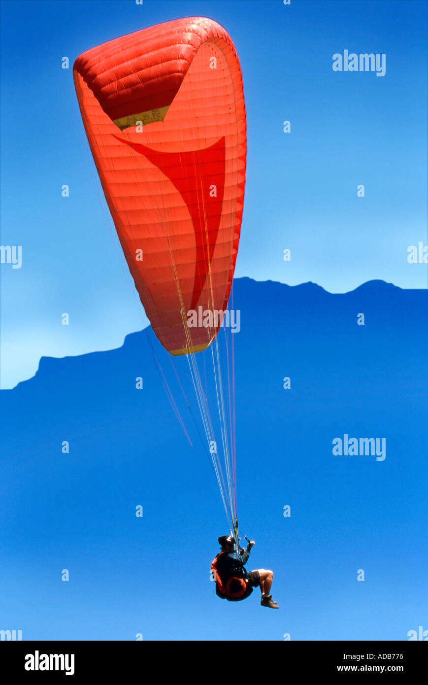 Hang gliding in sky with mountain in background Stock Photo