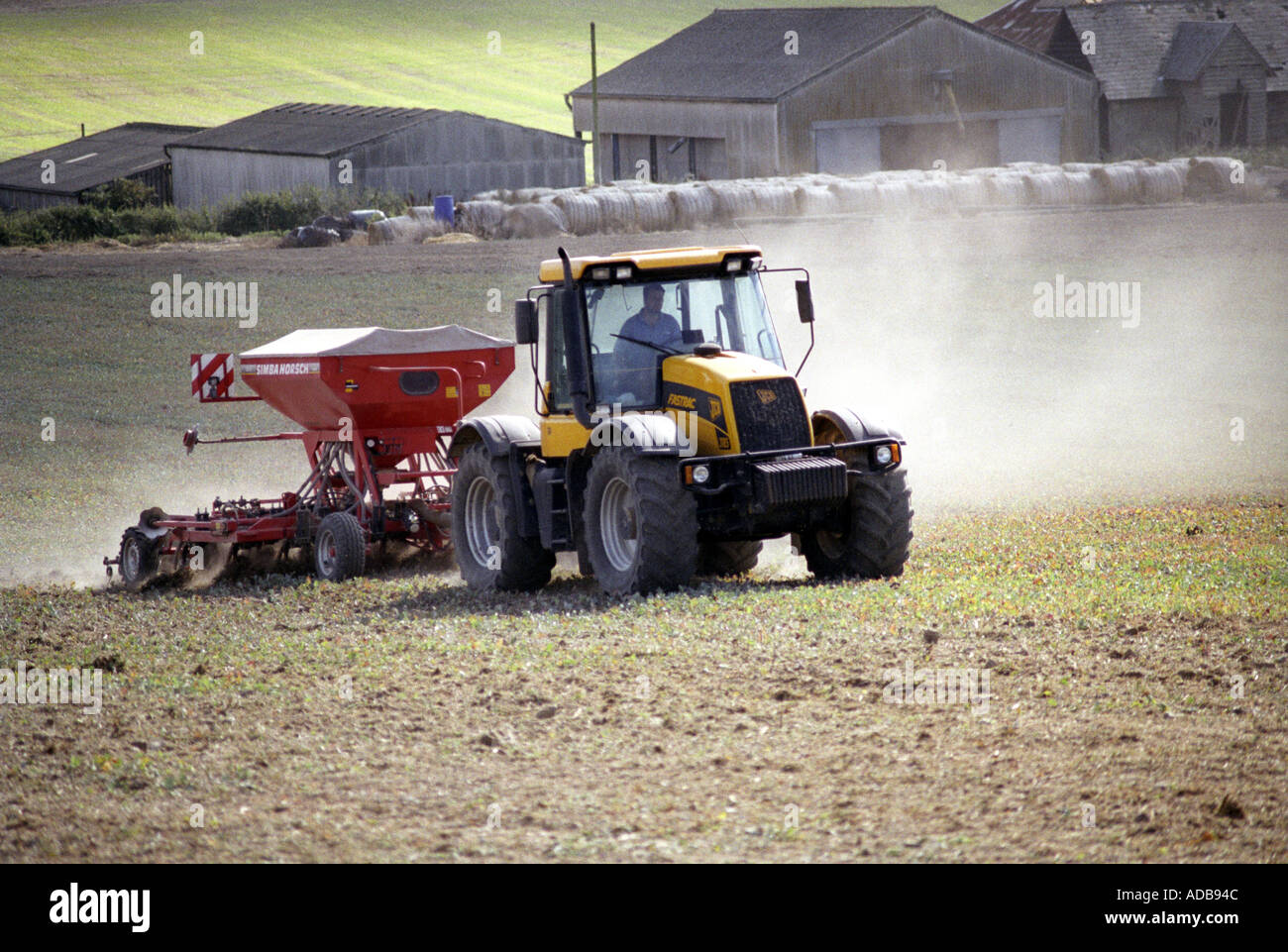Yellow tractor spreading fertiliser on a field near Salisbury Stock ...
