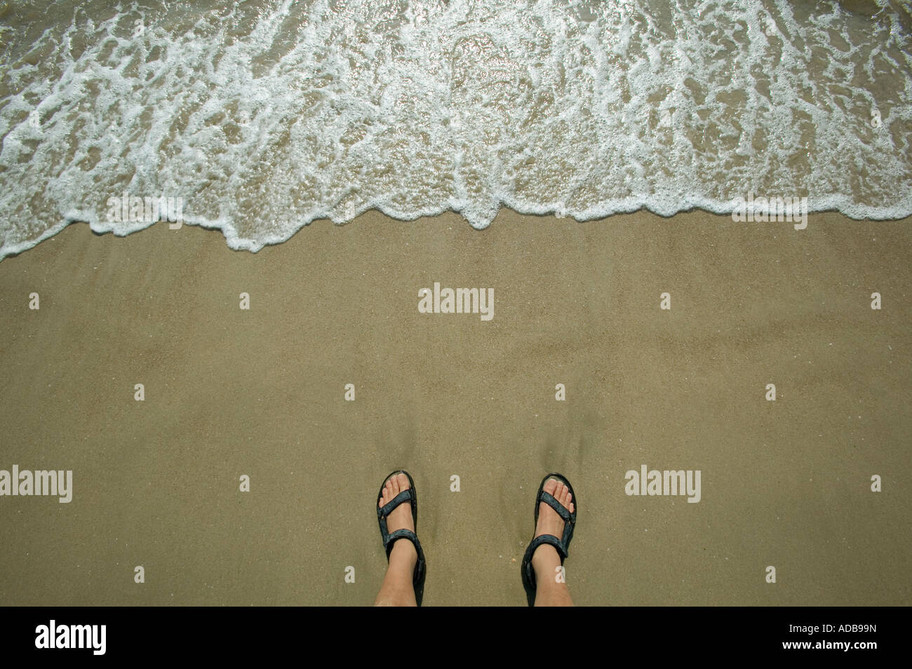 Overhead shot of feet on beach with waves Stock Photo