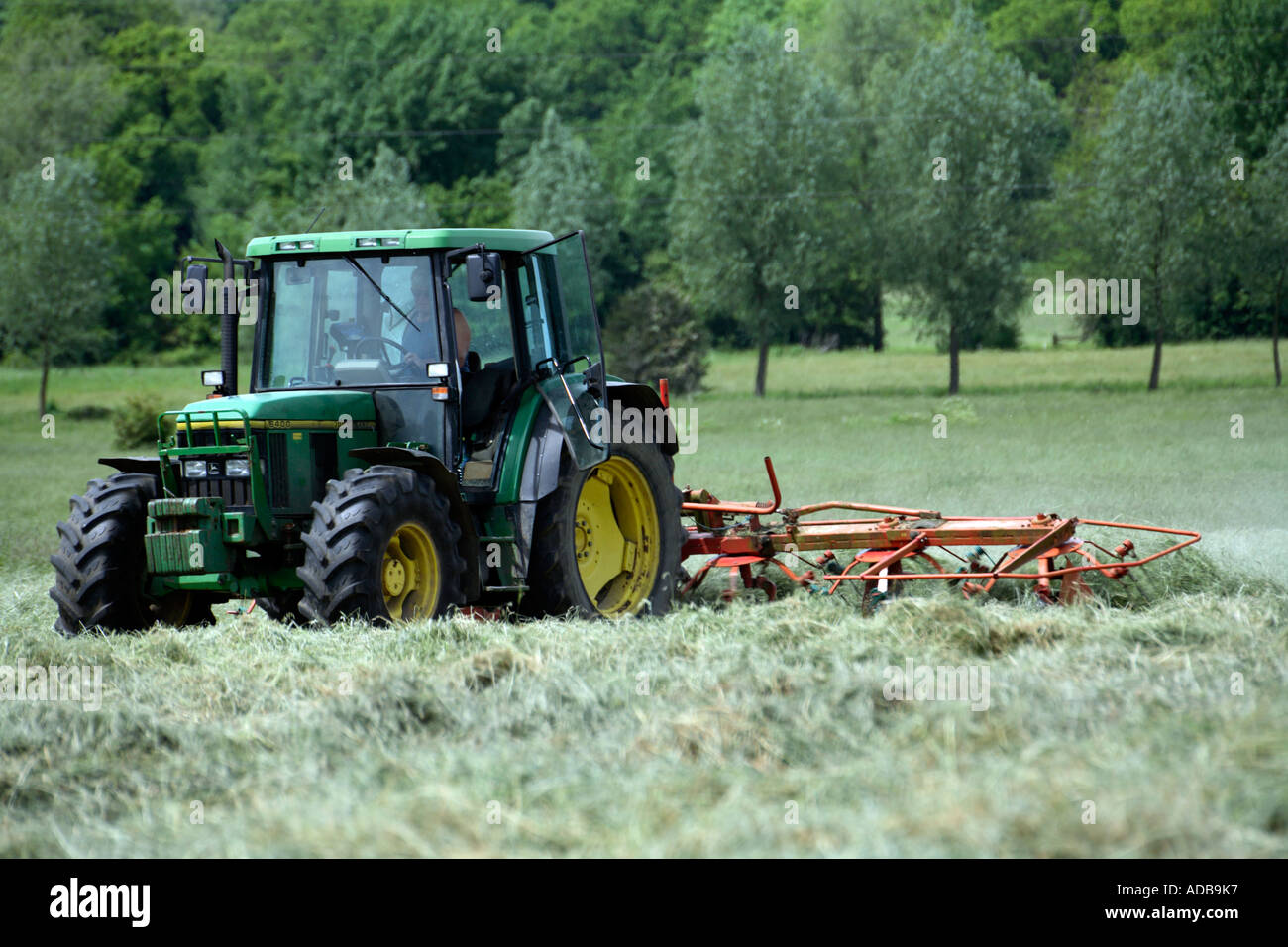 Tractor turning grass for hay 3 Stock Photo Alamy