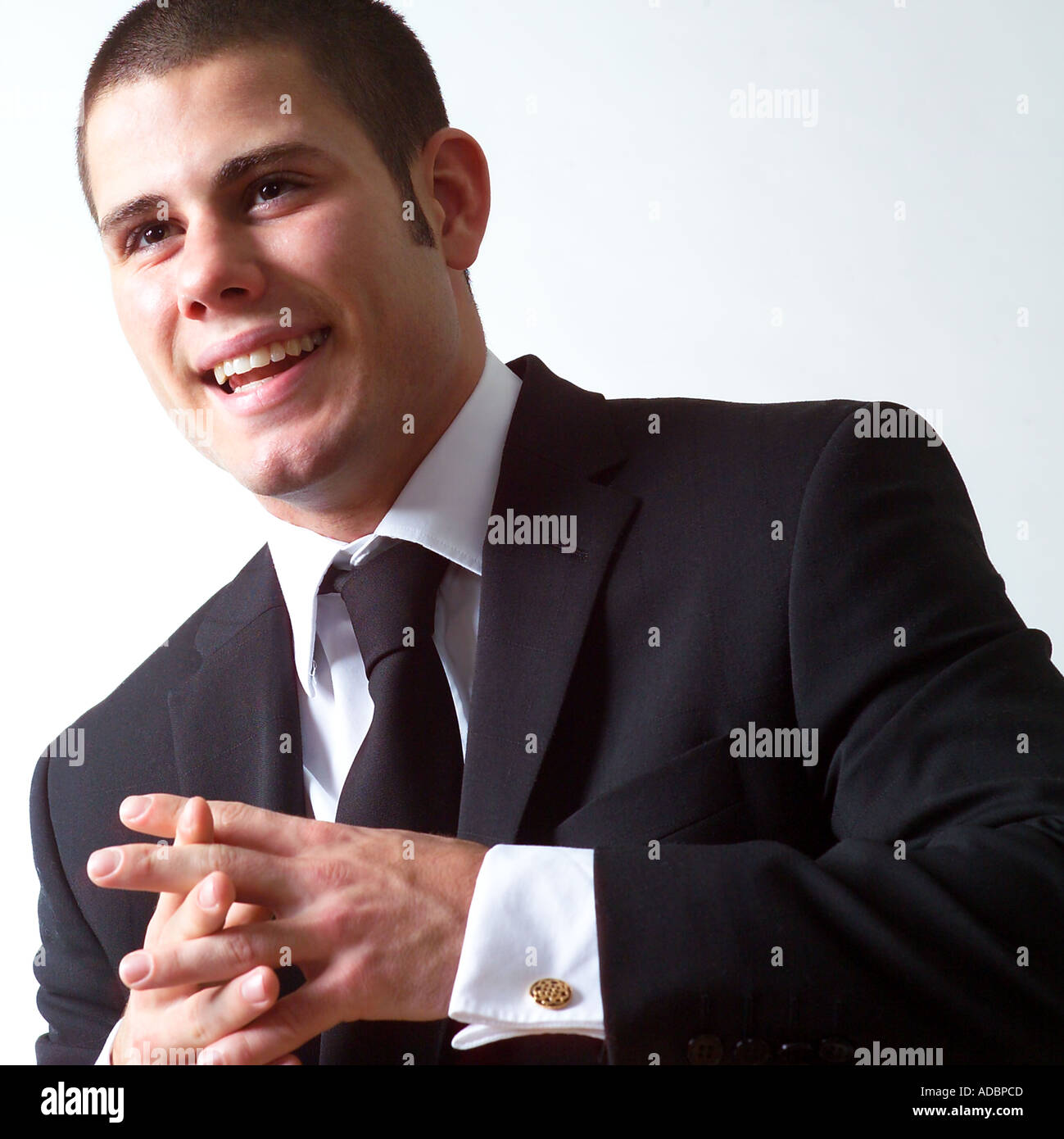 Businessman clasping hands and smiling, studio shot Stock Photo