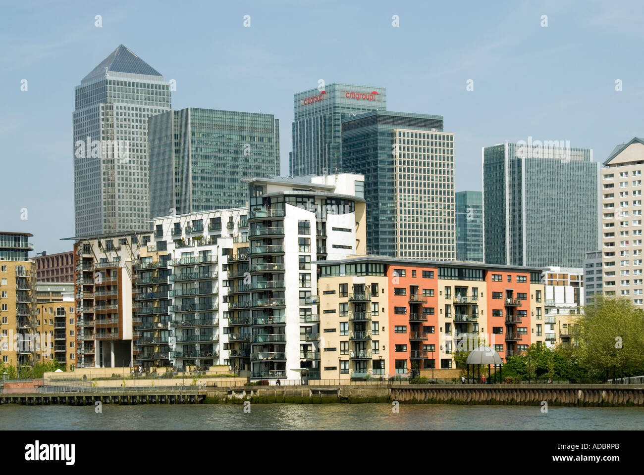 River Thames riverside apartment blocks in front of Docklands Canary Wharf redevelopment complex on the Isle of Dogs in Tower Hamlets East London UK Stock Photo