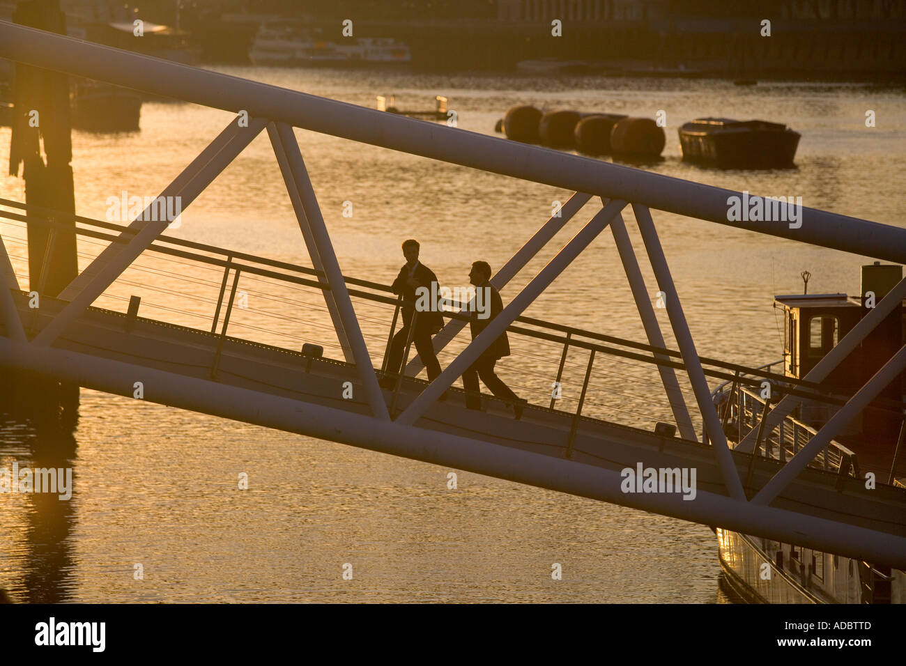 Pedestrians walk up a ramp from a floating boat bar along th Thames River in London Stock Photo
