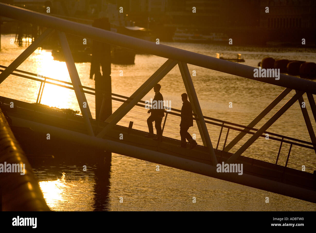 Pedestrians walk up a ramp from a floating boat bar along the Thames River in London Stock Photo