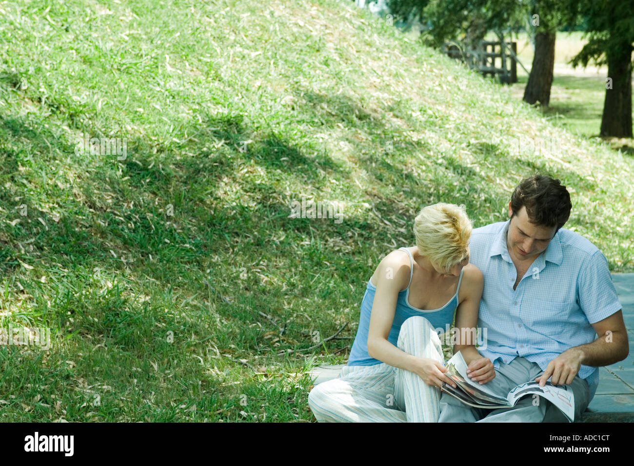 Couple sitting outdoors, looking at catalog together Stock Photo Alamy