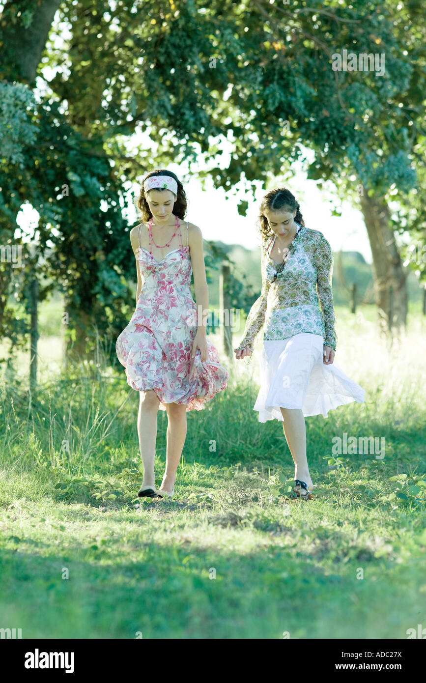 Two young women walking through field Stock Photo - Alamy
