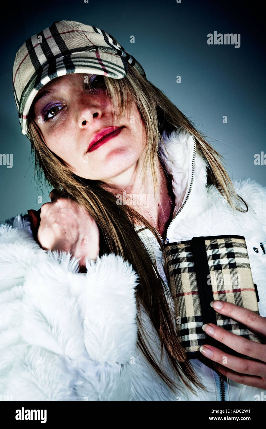 A young woman wearing a white fur jacket, a Burberry baseball cap and holding a Burberry purse Stock Photo