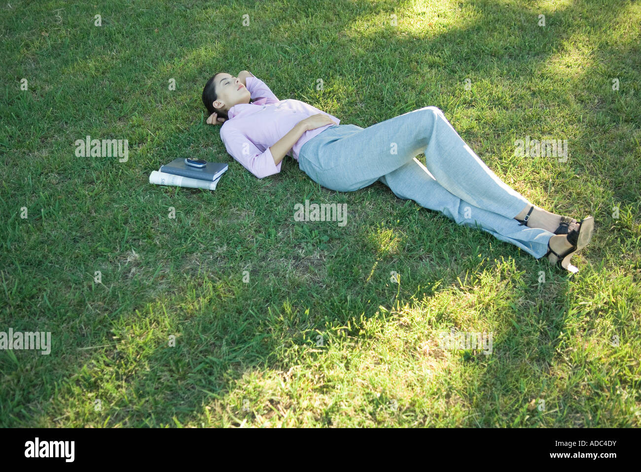 Businesswoman lying in grass, eyes closed Stock Photo