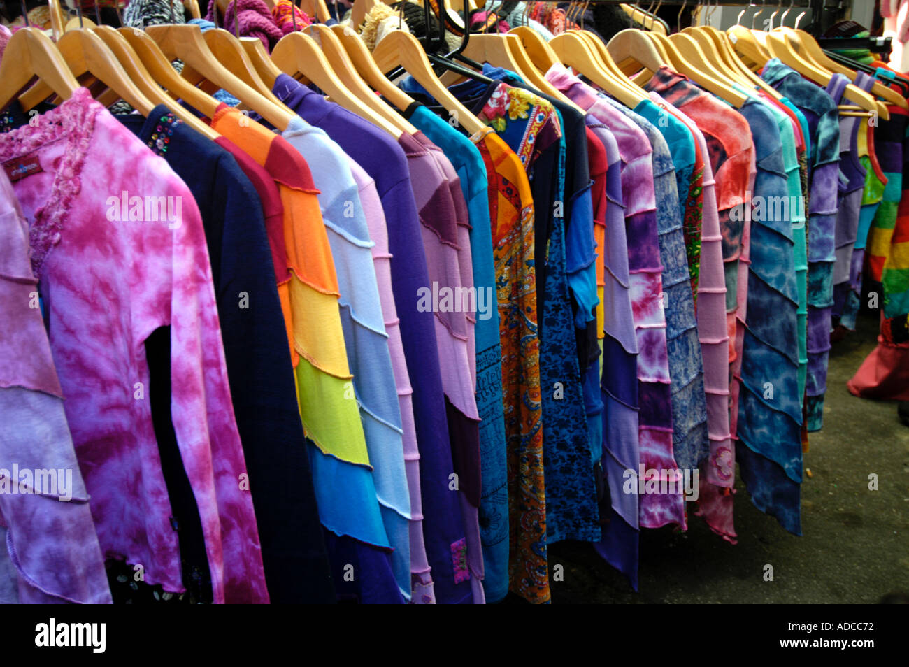 Colourful dyed clothes on hangers at stall at Camden Market London England UK Stock Photo