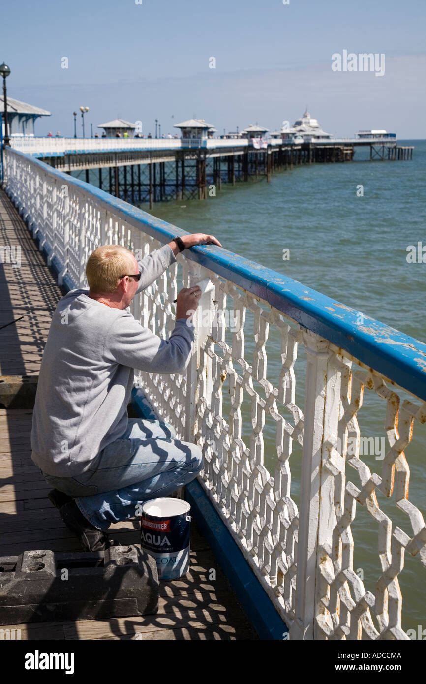 Painting metal railings white on Llandudno pier Wales UK Stock Photo