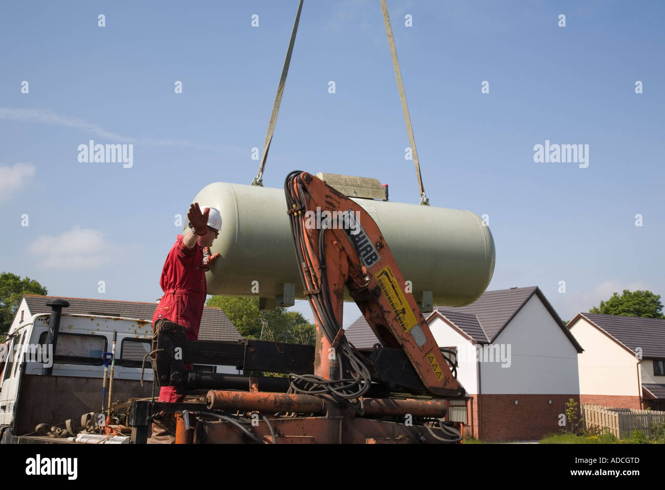 Calor gas tank being lowered on to a lorry by a crane against blue sky Stock Photo