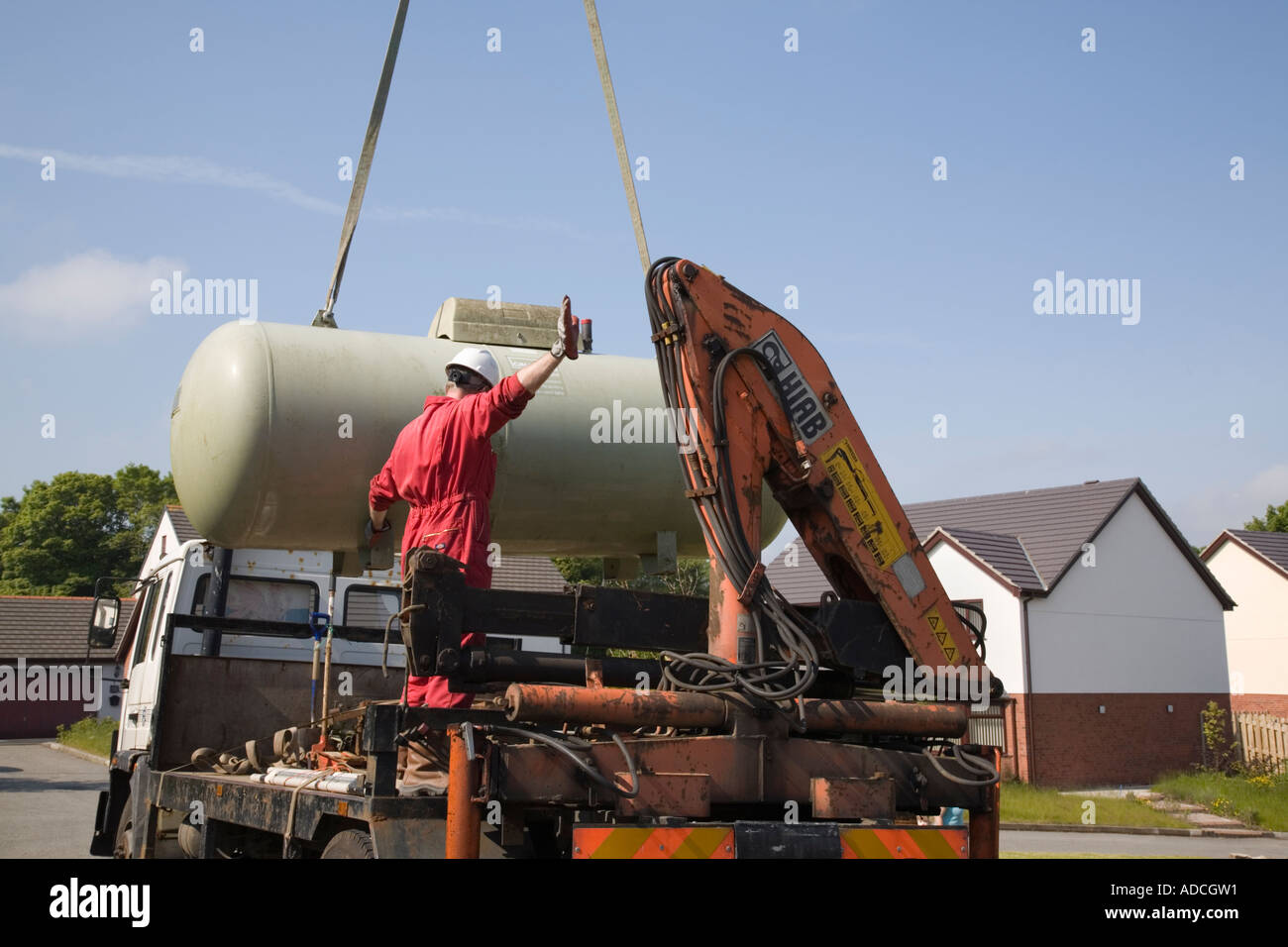 Calor gas tank being lowered on to a lorry by a crane against blue sky Stock Photo