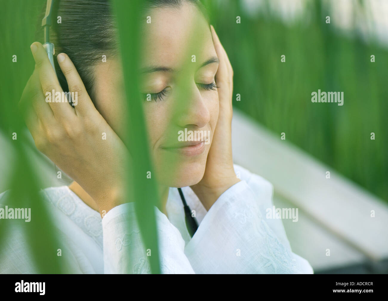 Woman listening to headphones, eyes closed, hands over ears Stock Photo