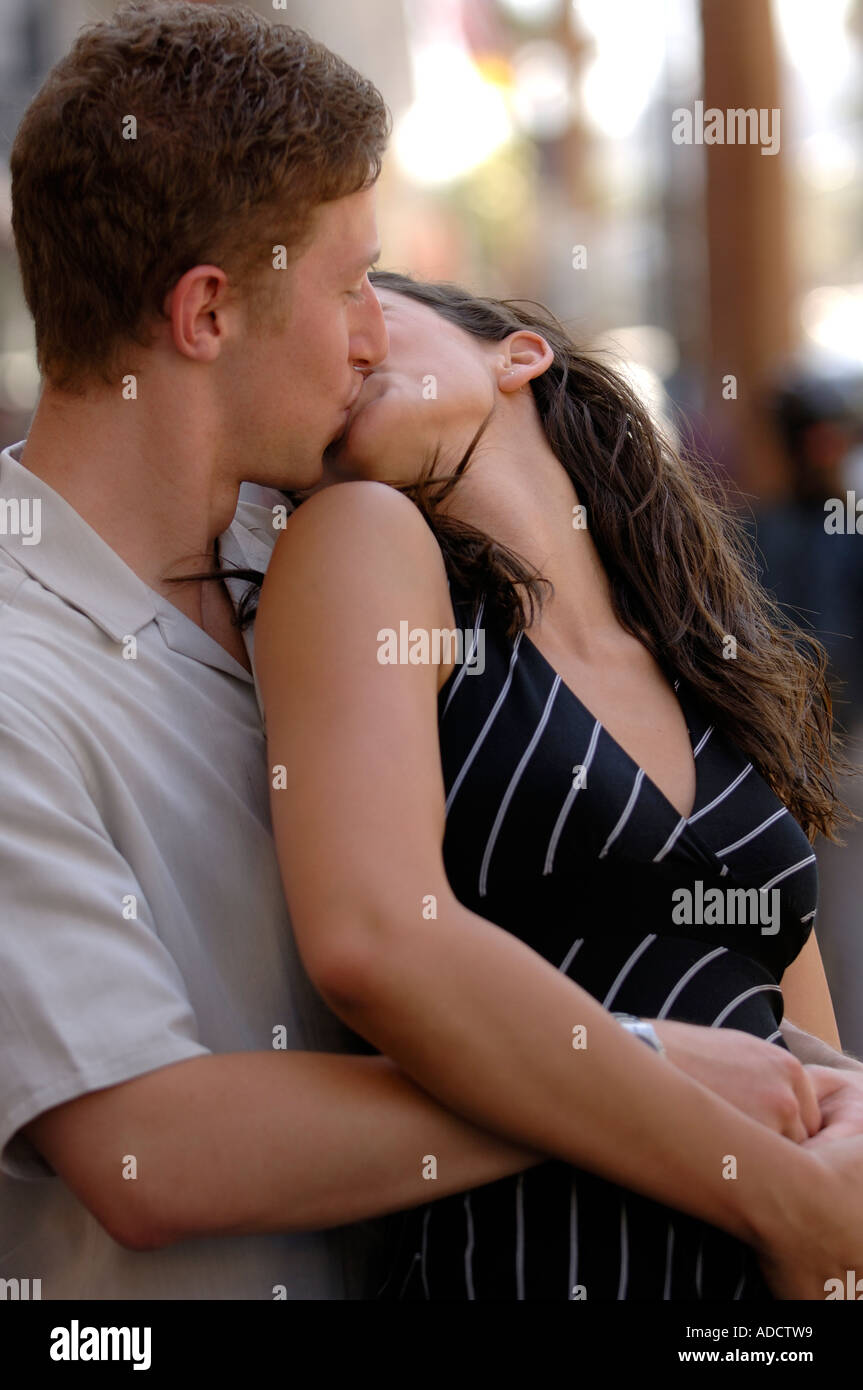 Young couple hugging and kissing in the middle of the street ...