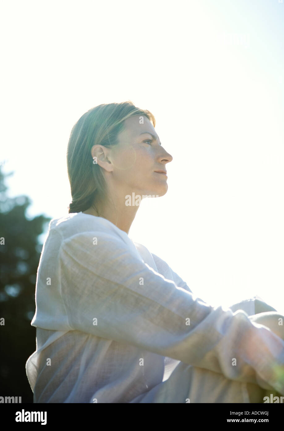 Woman sitting outdoors, low angle view Stock Photo