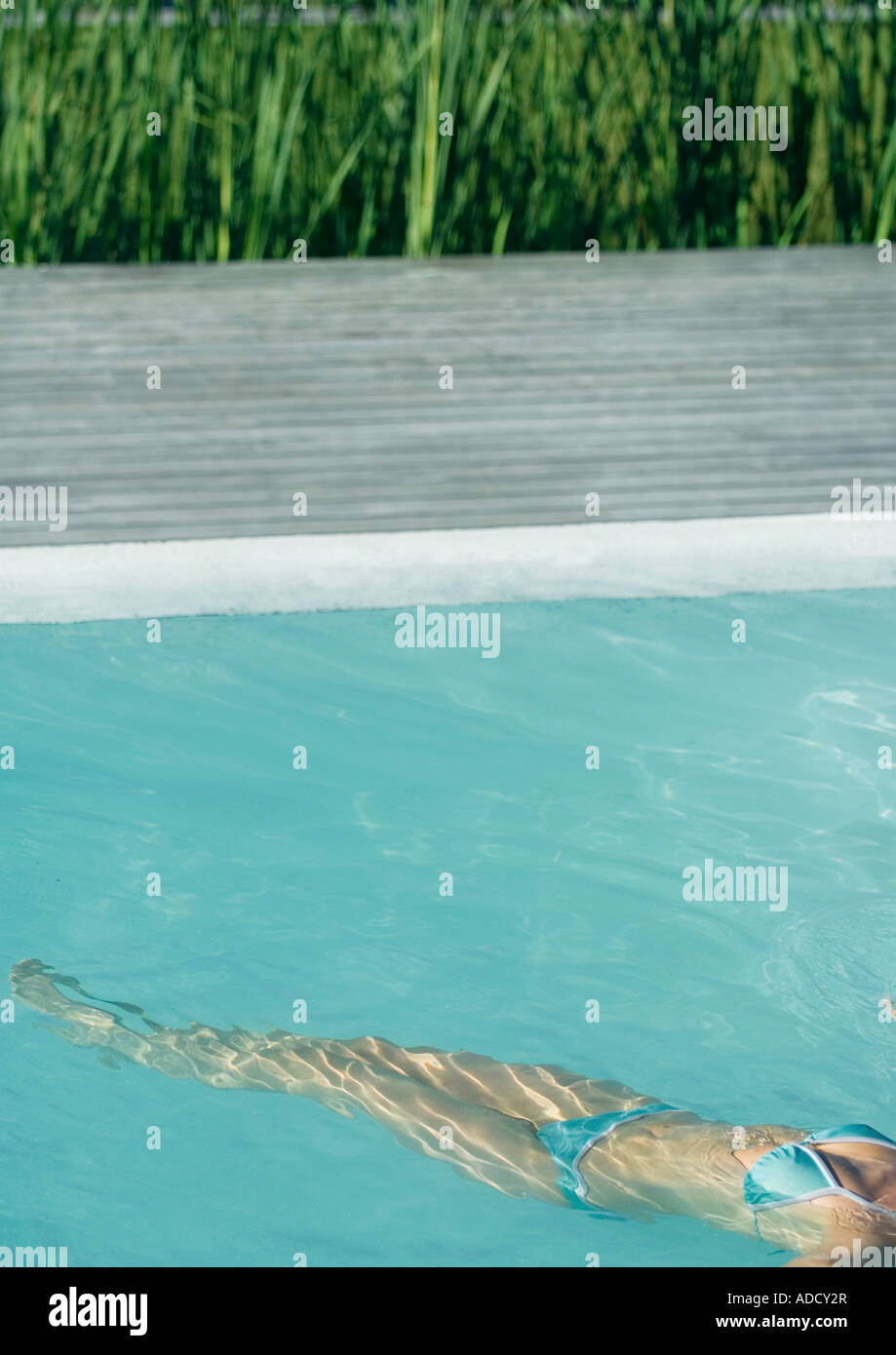 Woman floating on back in pool, neck down, high angle view Stock Photo