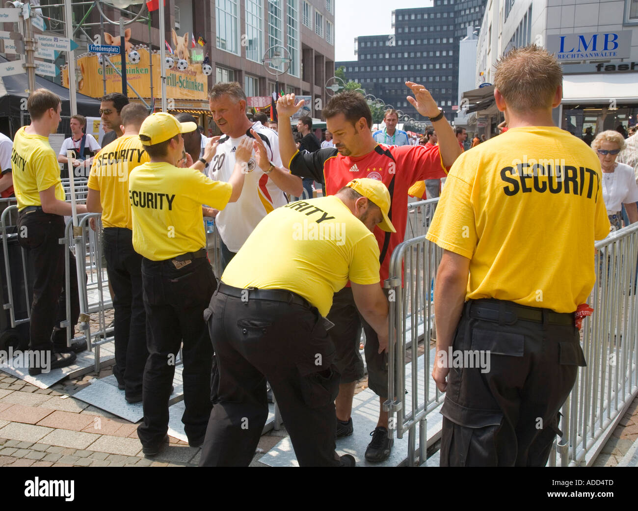 Security staff checking football fans at the entrance of a public