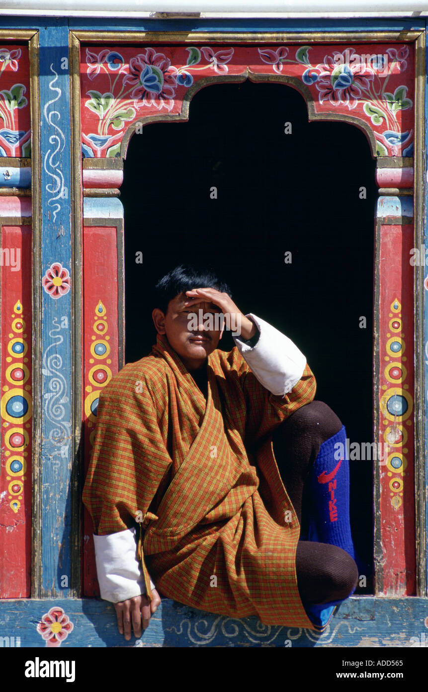 Bhutanese man shields eyes from sun Modern Nike sports socks worn with traditional outfit Paro Bhutan Stock Photo