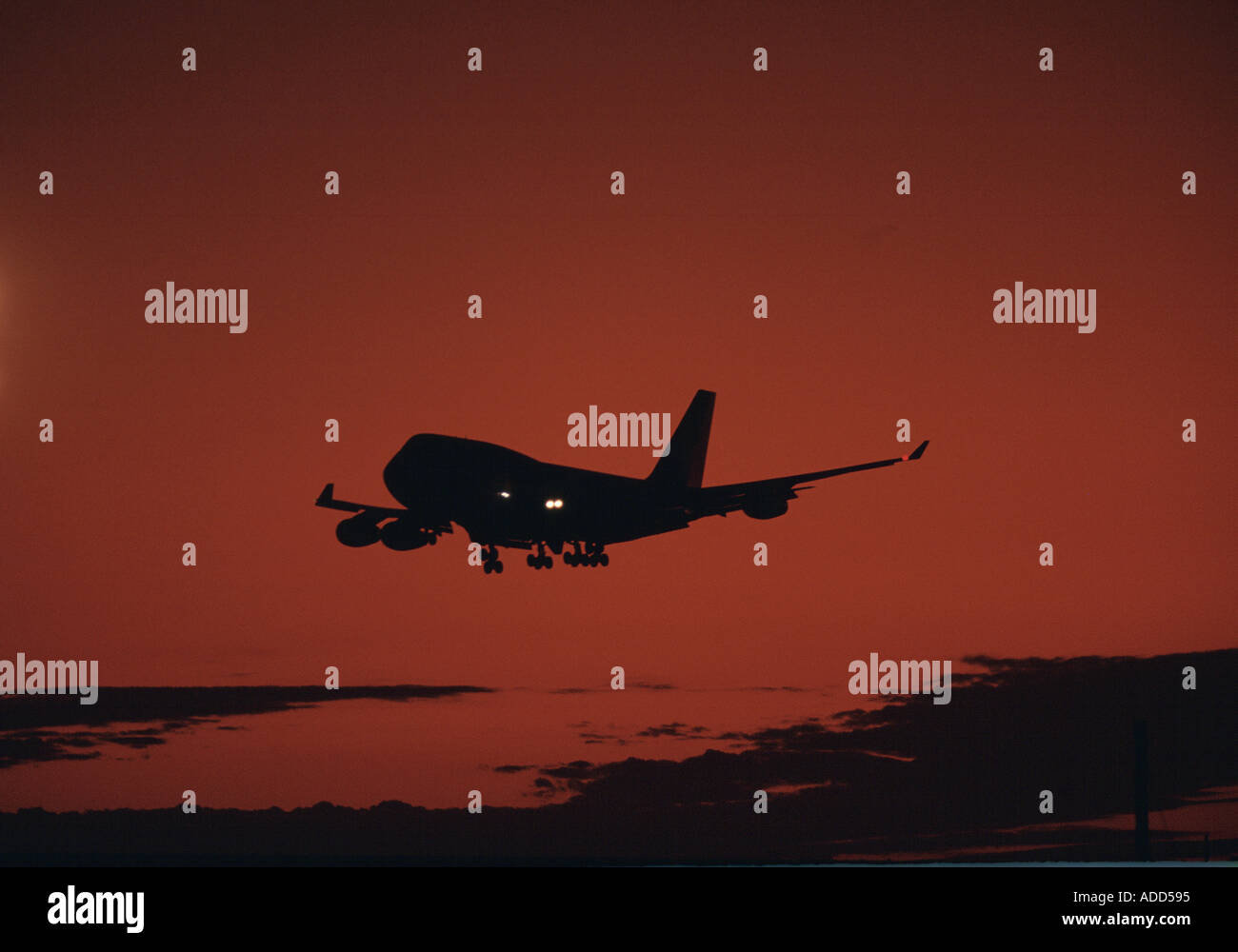 Jet aircraft forms a silhouette against dark red skies over Australia Stock Photo