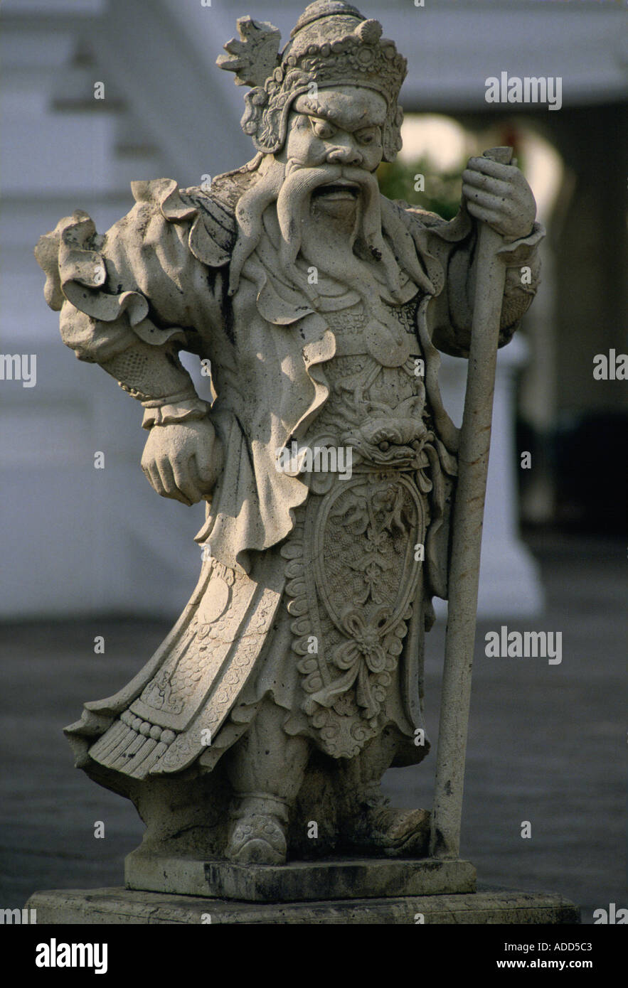 Ancient stone statue ofman dressed in long robes holding a staff at the Grand Palace Bangkok Thailand Stock Photo