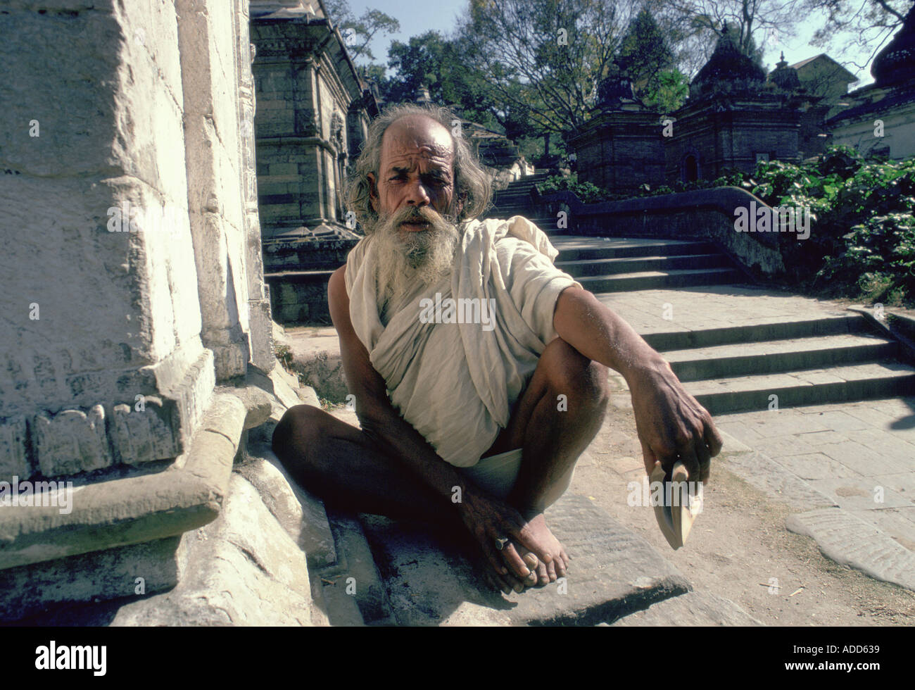 Holy man crouching at the Hindu Pashupatinath Temple on the Bagmati River in Nepal Stock Photo