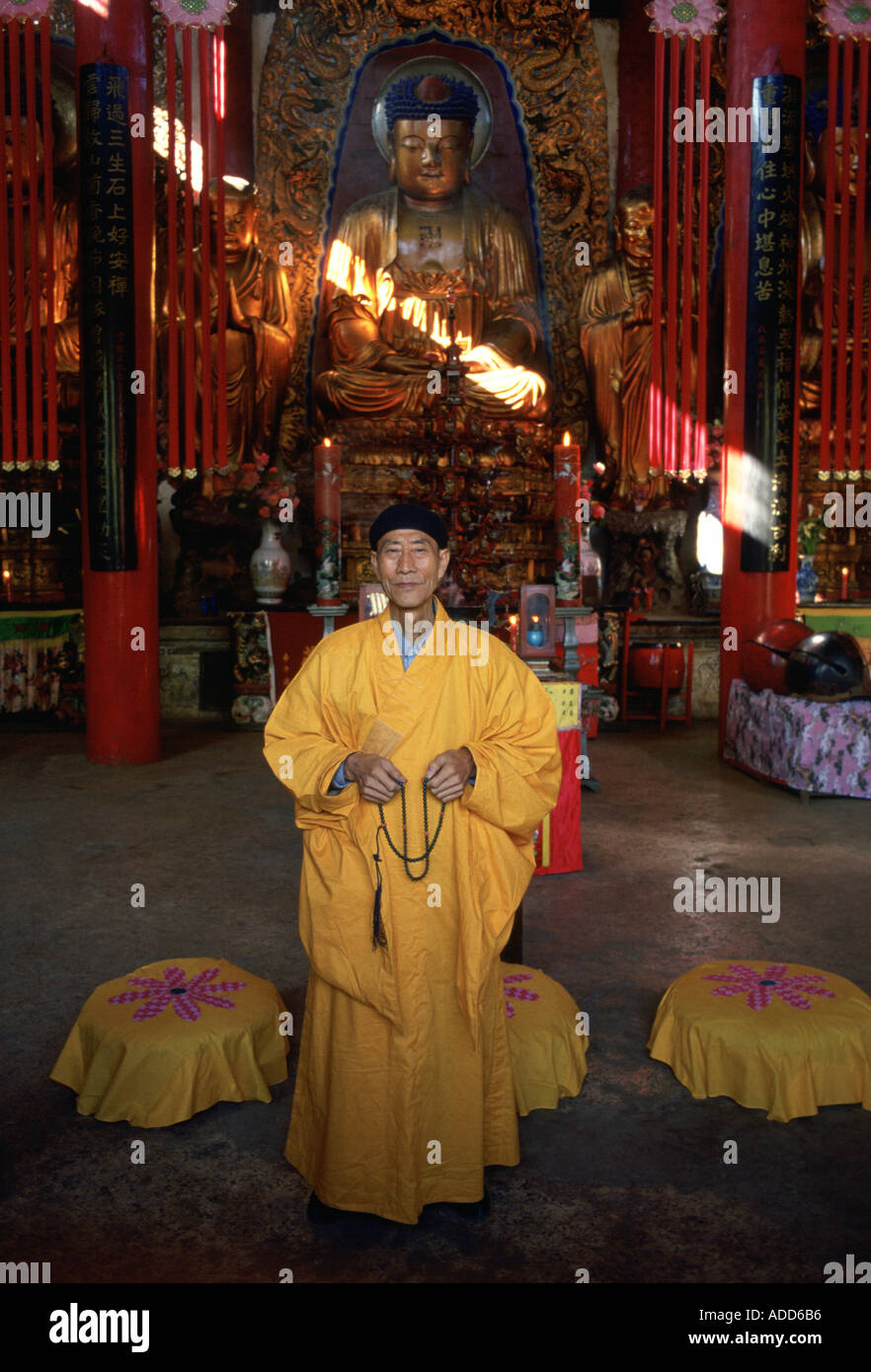Buddhist monk in saffron robes praying at Buddha statue at the Buddhist Temple in Huating China Stock Photo