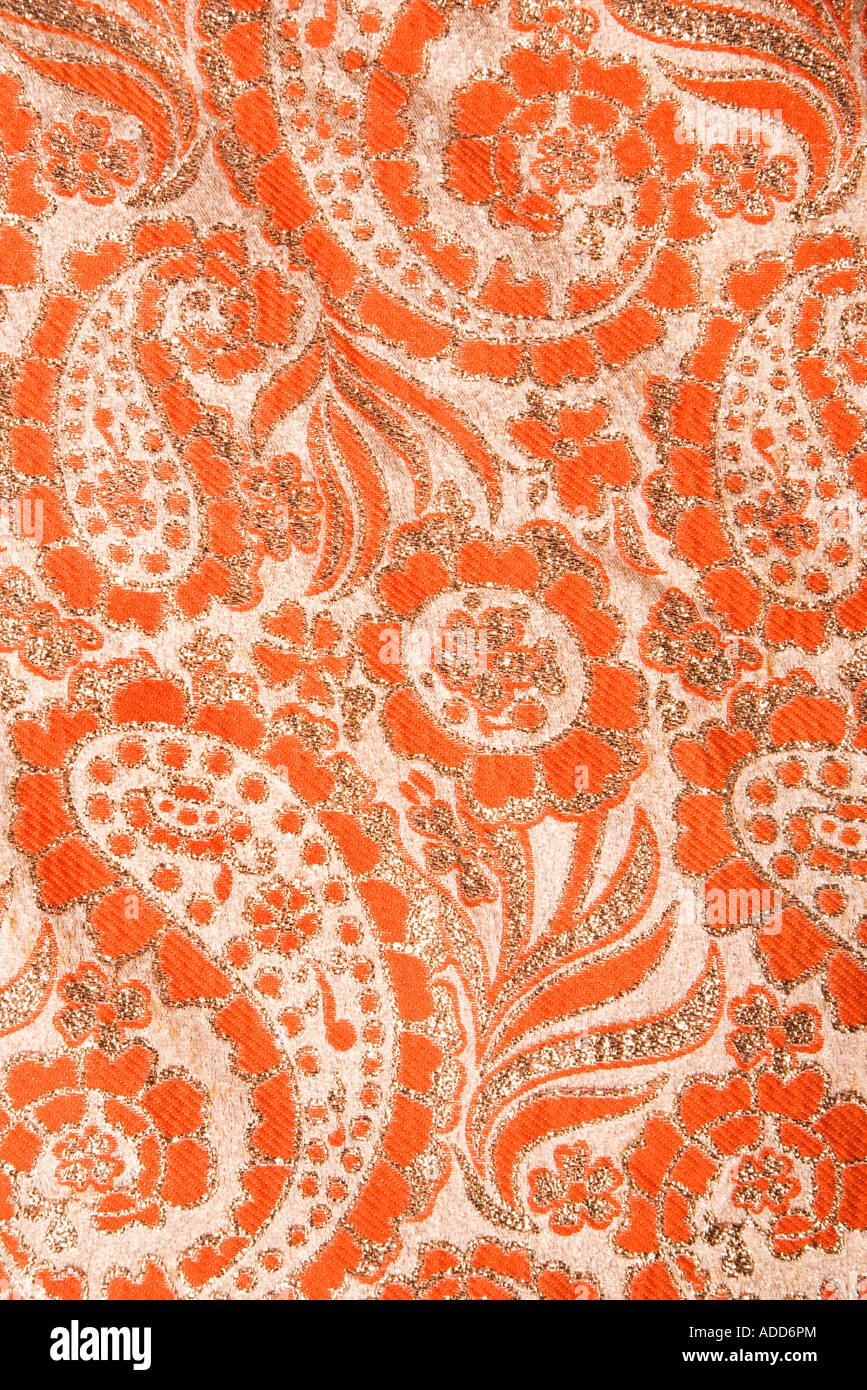 Close up of orange textural vintage fabric with paisley and metalic thread stitching Stock Photo