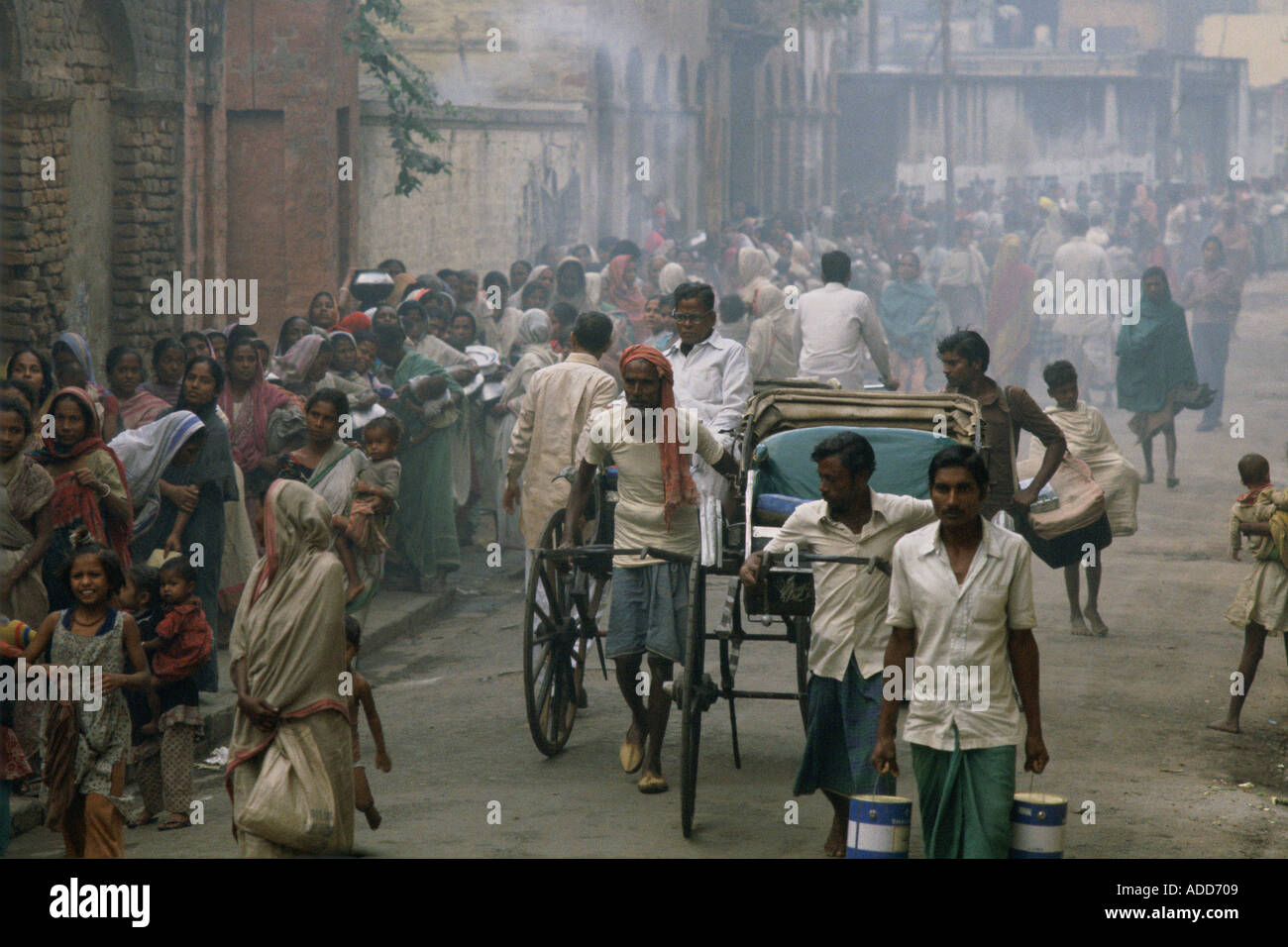 Rickshaws pass poor queuing for food early morning at Mother Teresa s Mission Calcutta India Stock Photo