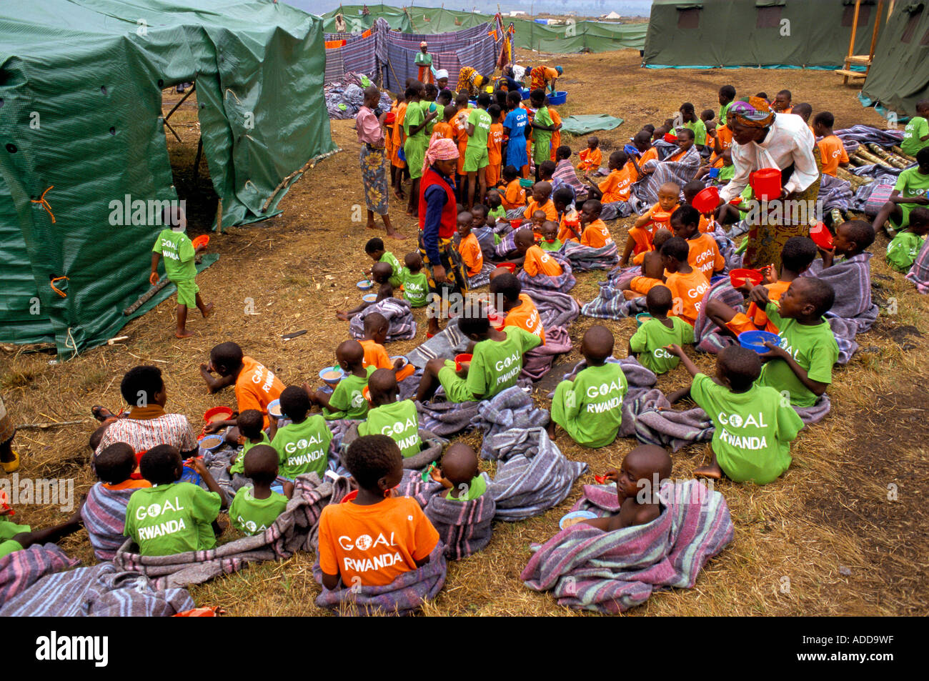 Kibumba orphanage Goma, DRC:  Young children in orange green Goal t-shirts having breakfast on the ground. Stock Photo