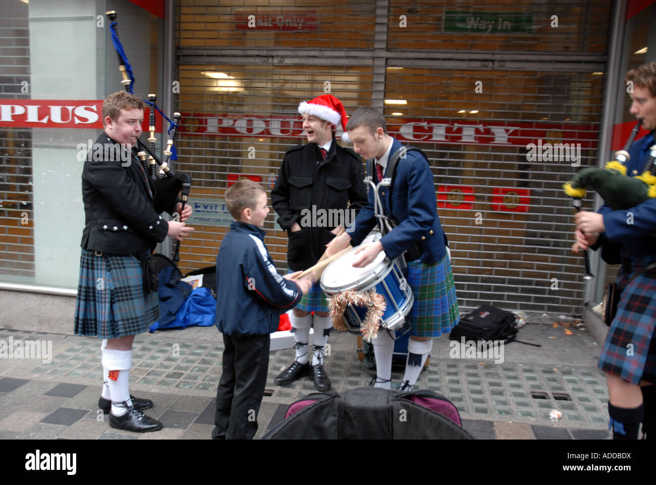 Young Boy Playing The Drums Of  Scots Pipers Entertaining the Public on Christmas Eve. Sauchiehall Street. Glasgow. Scotland. Stock Photo