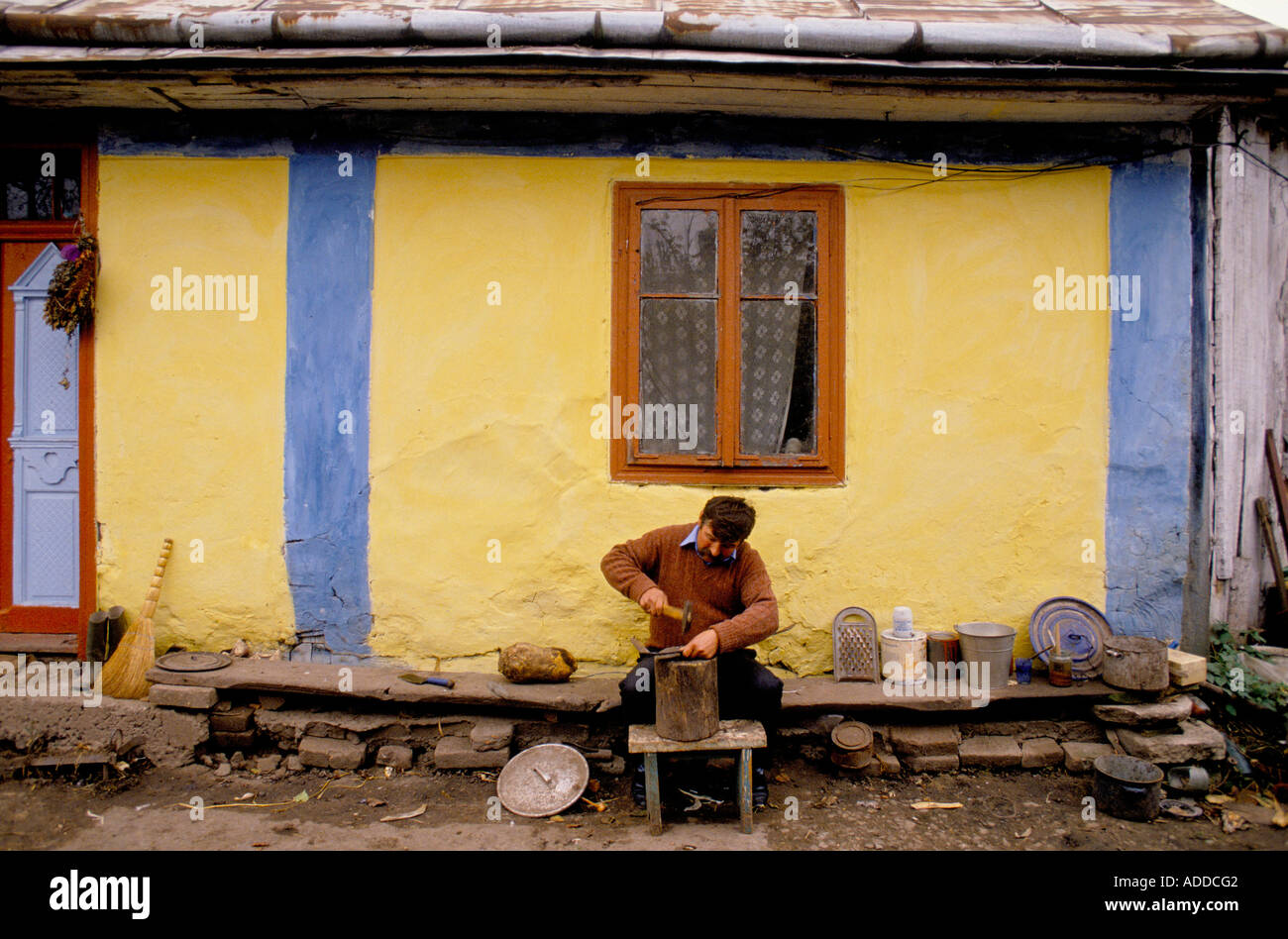 A farmer repairing his sickle in his back yard Lviv Western Ukraine Stock Photo