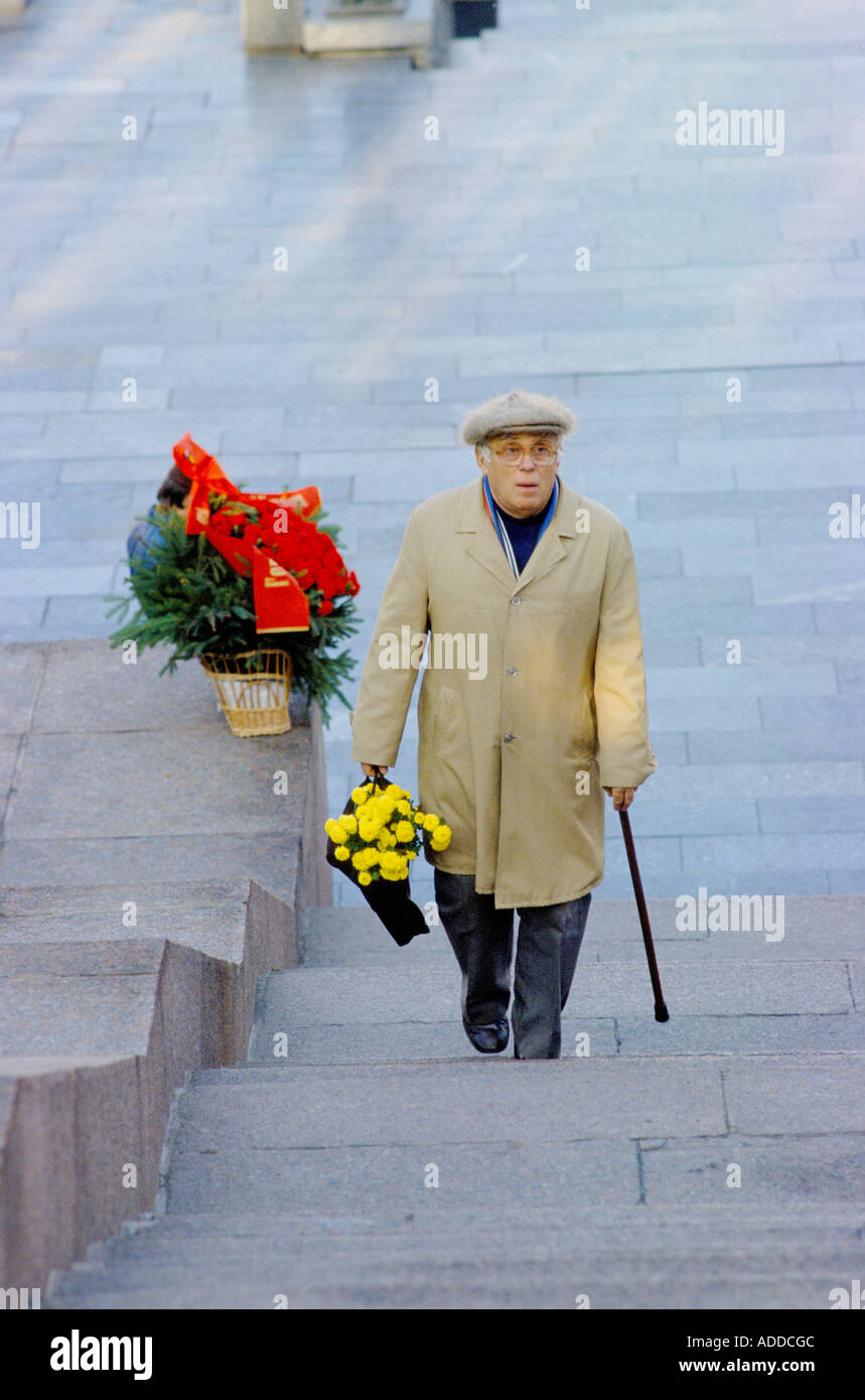 A man brings flowers to leave at the war memorial on October day Stock Photo