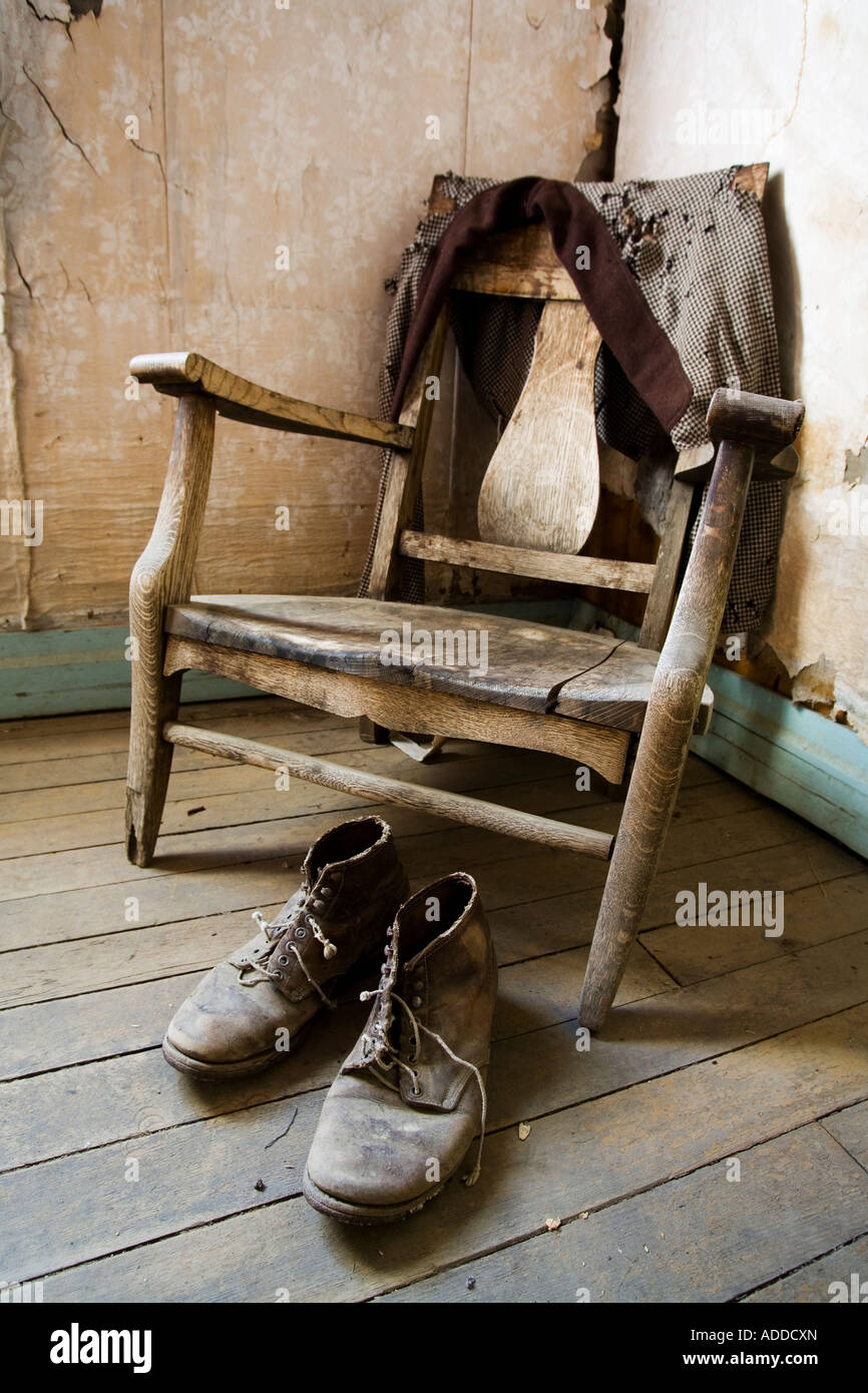 Old wooden chair a pair of work boots and a worn tattered jacket. Stock Photo
