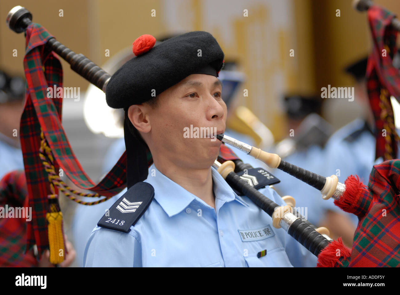 Chinese policeman wearing the traditional Scottish Balmoral hat blowing