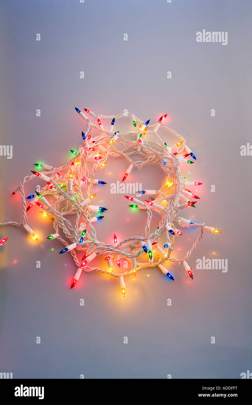 One strand of multi colored Christmas tree lights coiled together with blue tint dark studio portrait Stock Photo