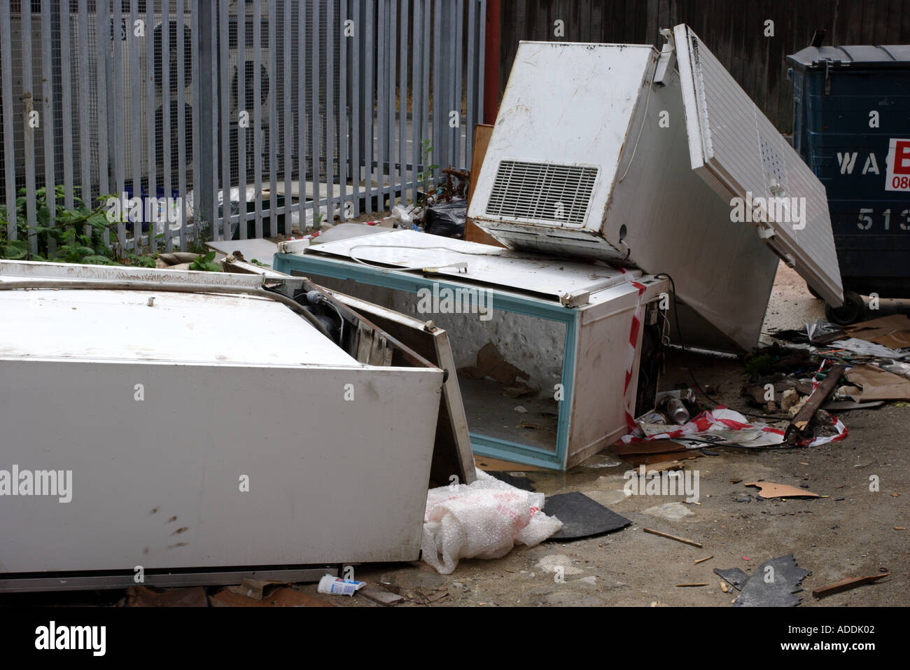 Abandoned fridges and freezers in a back alley behind a parade of shops