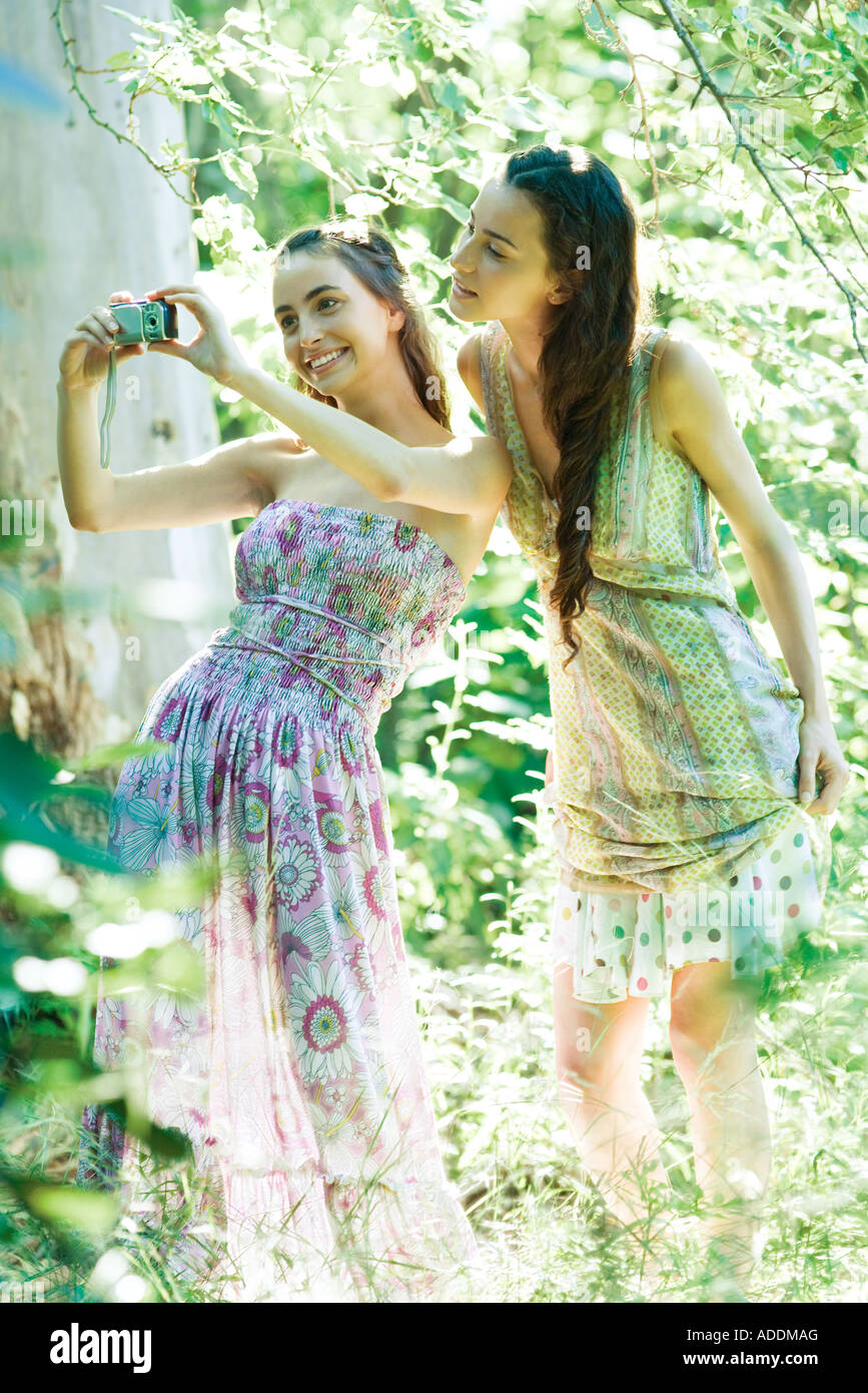 Two young women wearing sun dresses standing in forest taking photo with digital camera Stock Photo Alamy